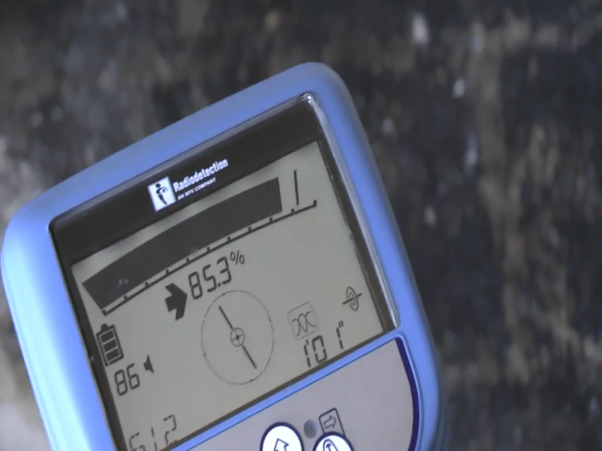 Handheld electronic pipe locator display showing signal strength while tracing an underground leak