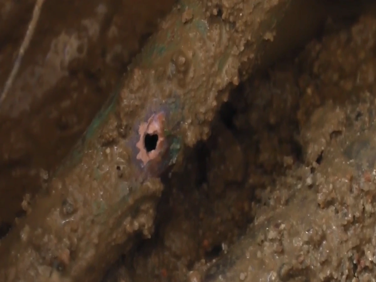 Close-up of a small corrosion hole in a buried pipe found during underground leak detection in Torrance
